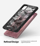 Galaxy A71 Case | Fusion-X - A black rugged phone case with a camo back hovering over a pink smartphone.