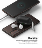 Galaxy Note 20 Case | Air - A smartphone in a clear case charging wirelessly while powering white earbuds on its back.