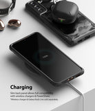 Galaxy S21 Case | Fusion-X - A phone in a rugged case charging wirelessly with earbuds resting on a second phone nearby.