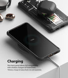 Galaxy S21 Case | Fusion-X Design - Smartphone in a black case wirelessly charging on a pad with earbuds nearby.