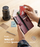 Galaxy S21 Plus Case | Folio Signature+ - Hand inserting a debit card into a maroon leather wallet phone case.