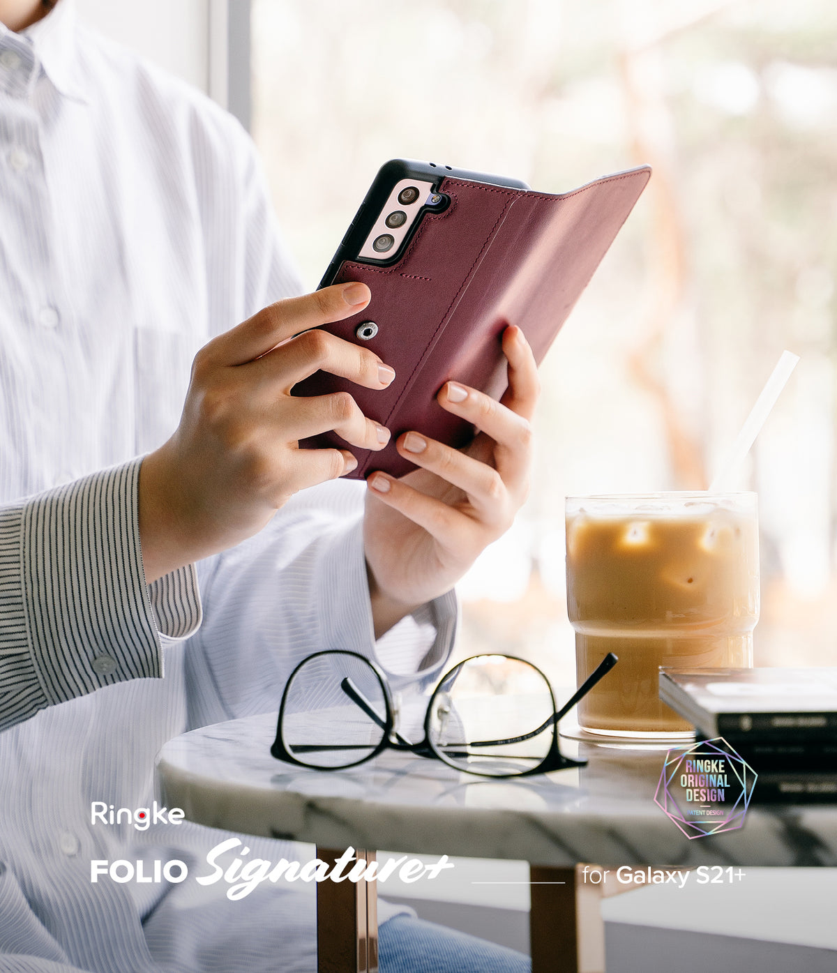 Galaxy S21 Plus Case | Folio Signature+ - Person holding a maroon leather folio phone case at a cafe table.