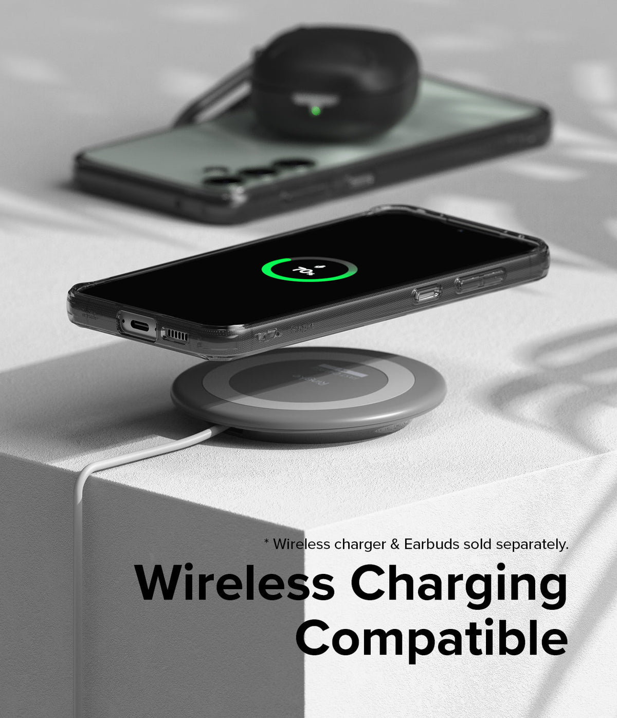 Galaxy S23 FE Case | Fusion - A smartphone in a clear case wirelessly charging on a pad, with earbuds resting on another phone.