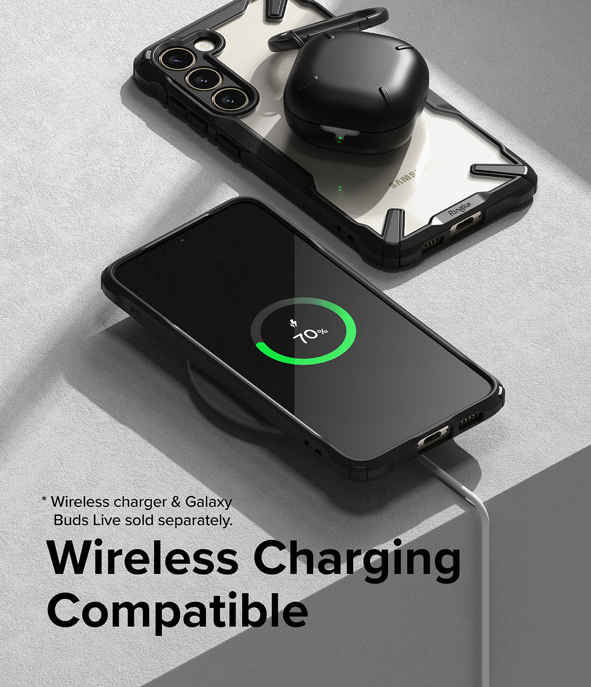 Galaxy S23 Plus Case | Fusion-X - A phone in a black protective case wirelessly charging with earbuds resting on top.