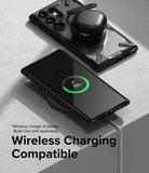 Galaxy S23 Ultra Case | Fusion-X - A phone in a black case wirelessly charging with earbuds resting on its back.