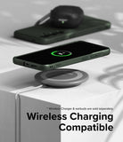 Galaxy S24 Case | Onyx - A dark green phone case charging wirelessly on a pad with earbuds in the background.