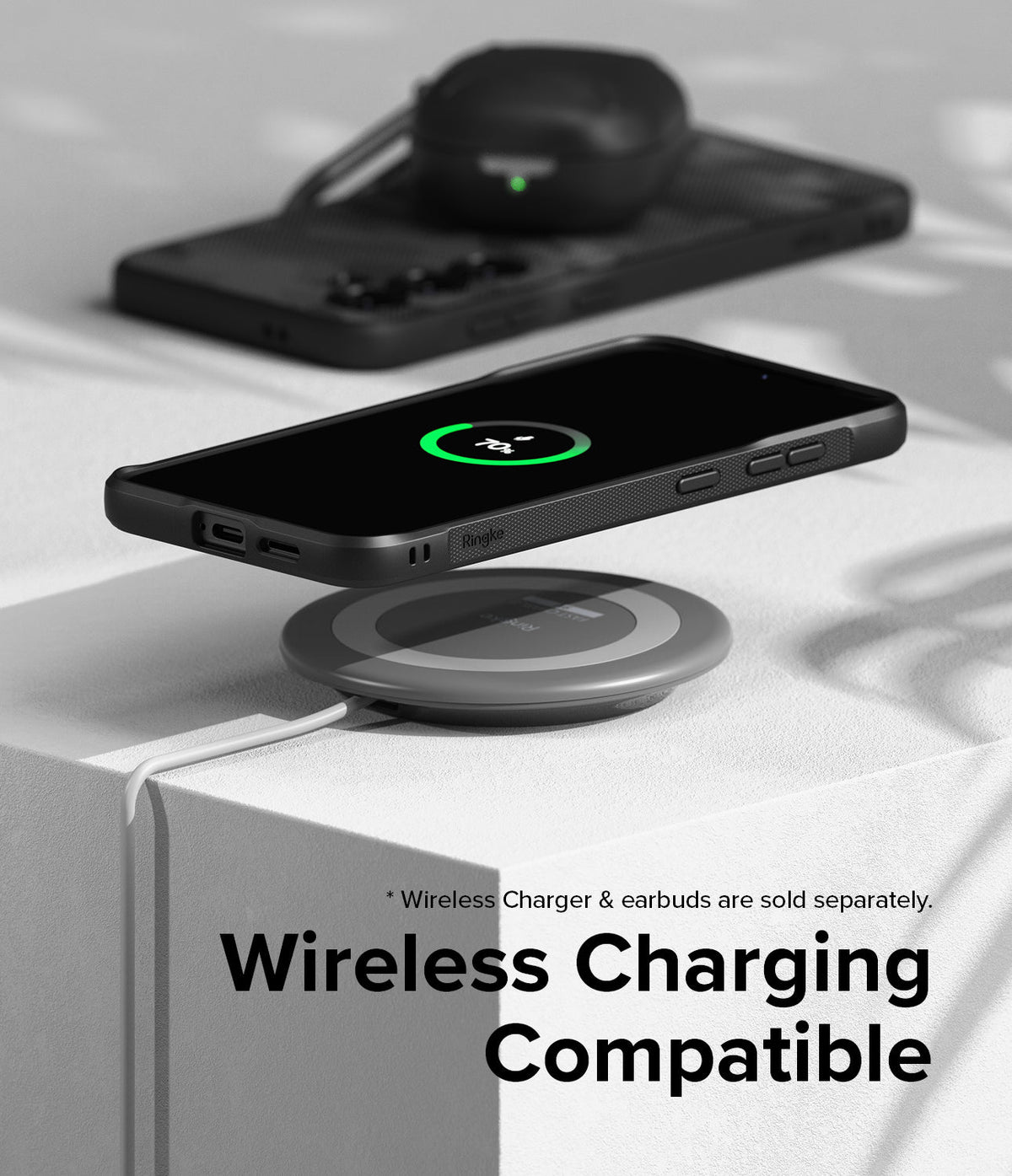 Galaxy S24 Plus Case | Onyx Design - Black phone in Onyx case wirelessly charging on a pad with earbuds in background.