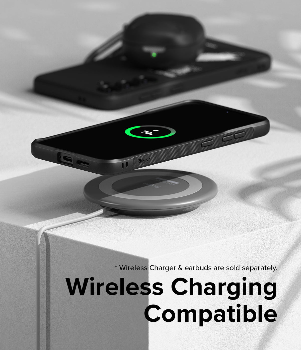 Galaxy S24 Plus Case | Onyx Design - Black phone in Onyx case wirelessly charging on a pad with earbuds in background.