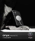 Galaxy S25 FE Case | Onyx Magnetic - Black textured phone case with a magnetic charging disc attached, resting on a rock.