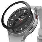 Galaxy Watch 4 Classic 46mm | Bezel Styling - A black adhesive bezel ring hovering above a silver Galaxy Watch 4.