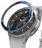 Galaxy Watch 4 Classic 46mm | Bezel Styling - Galaxy Watch 4 Classic 46mm | A blue metallic bezel ring hovering above a silver smartwatch with a black analog face.