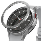 Galaxy Watch 4 Classic 46mm | Bezel Styling - Galaxy Watch 4 Classic 46mm | A silver textured bezel ring hovering above a silver smartwatch with a black watch face.
