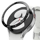 Galaxy Watch 5/4 40mm | Bezel Styling - A black adhesive watch bezel ring hovering above a silver smartwatch with a white band.