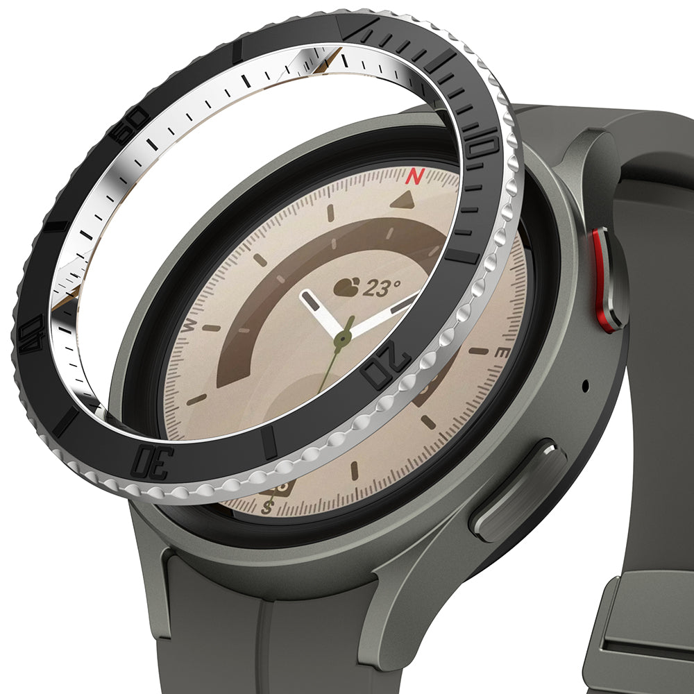 Galaxy Watch 5 Pro (45mm) | Premium Bezel Styling - Galaxy Watch 5 Pro (45mm) - A black metallic bezel styling ring hovering above a grey Galaxy Watch 5 Pro.