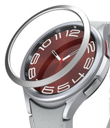 Galaxy Watch 6 Classic 47mm | Bezel Styling - Galaxy Watch 6 Classic 47mm | A silver metal bezel ring hovering above a smartwatch with a red face and white numbers.