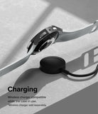 Galaxy Watch 6 44mm Case | Slim - A Galaxy Watch 6 with a slim case hovering above a wireless charging puck on a textured surface.