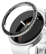 Galaxy Watch 9 / 8 40mm | Bezel Styling Premium - A close-up of a smartwatch with a white silicone strap, a black analog-style display face, and a silver-toned bezel with a textured outer ring.