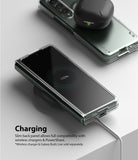 Galaxy Z Fold 3 Case | Slim - Folded phone in clear case wirelessly charging on a pad with earbuds resting on top.