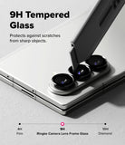 Galaxy Z Fold 7 | Camera Lens Frame Glass (2 Pack) - A utility knife blade scrapes against the 9H tempered glass camera lens protector on a silver smartphone.