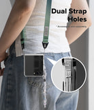 Galaxy Z Flip 8 Case | Fusion Flap Magnetic - A person wearing a clear phone case with a green adjustable strap and dangling charm, shown from the back over blue jeans. Large text reads 'Dual Strap Holes' with a note that accessories are sold separately, and a circular inset shows the strap attachment detail.