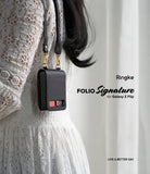 Galaxy Z Flip Case | Folio Signature Black - Person in white lace dress wearing a black leather phone case on a strap.