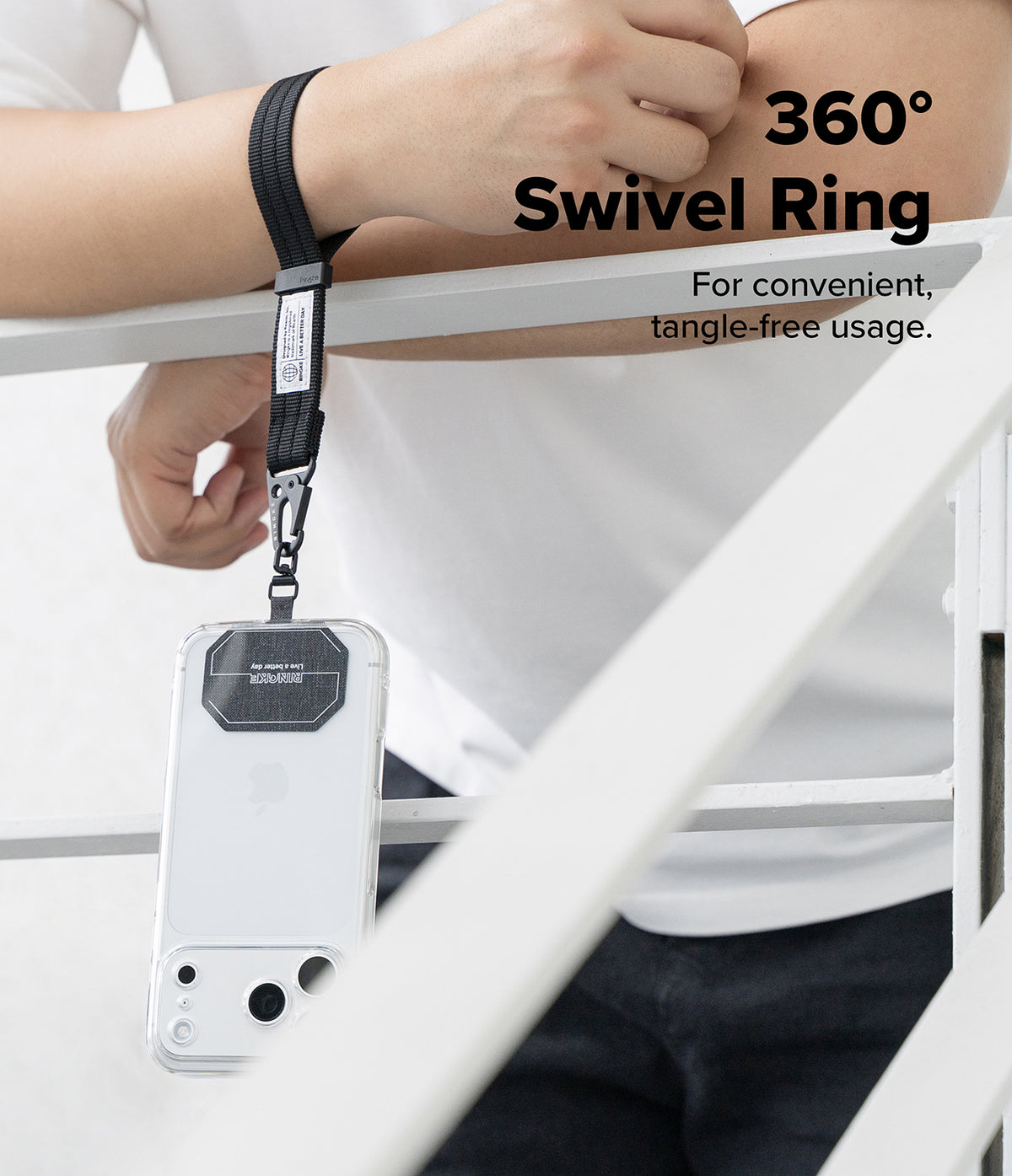 Holder Link Tactical Cam Buckle Hand Strap - A black swivel ring wrist strap with a metal clip holding a white smartphone case, shown being worn on a person's wrist while leaning on a white railing. Text on the image reads '360° Swivel Ring' and 'For convenient, tangle-free usage.