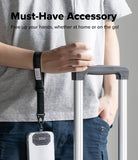 Holder Link Tactical Cam Buckle Hand Strap - A person wearing a gray t-shirt and blue jeans holds a white cup next to a rolling suitcase, with a black wrist strap accessory hanging from the suitcase handle. The text at the top reads 'Must-Have Accessory' and 'Free up your hands, whether at home or on the go!'.