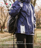 Holder Link Strap | Clear - Person wearing a phone on a black and white lanyard over a blue jacket and backpack in a park.