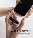 Holder Link Strap | Black - Hands holding a clear phone case with a black adhesive-free strap anchor attached at the bottom.