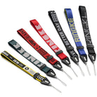 Hand Strap | Lettering - Six colorful fabric wrist straps with unique text designs and black plastic connectors with thin loops.