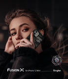 iPhone 12 Mini Case | Fusion-X - A woman holding a camo-patterned Fusion-X phone case against her ear in a dark setting.
