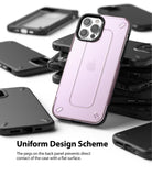 iPhone 12 / 12 Pro Case | [UX] - A translucent pink phone case with protective rear pegs resting on a stack of black cases.