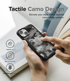 iPhone 14 Case | Fusion-X - Hands holding a black iPhone 14 case with a tactile, layered camouflage pattern and feature icons.