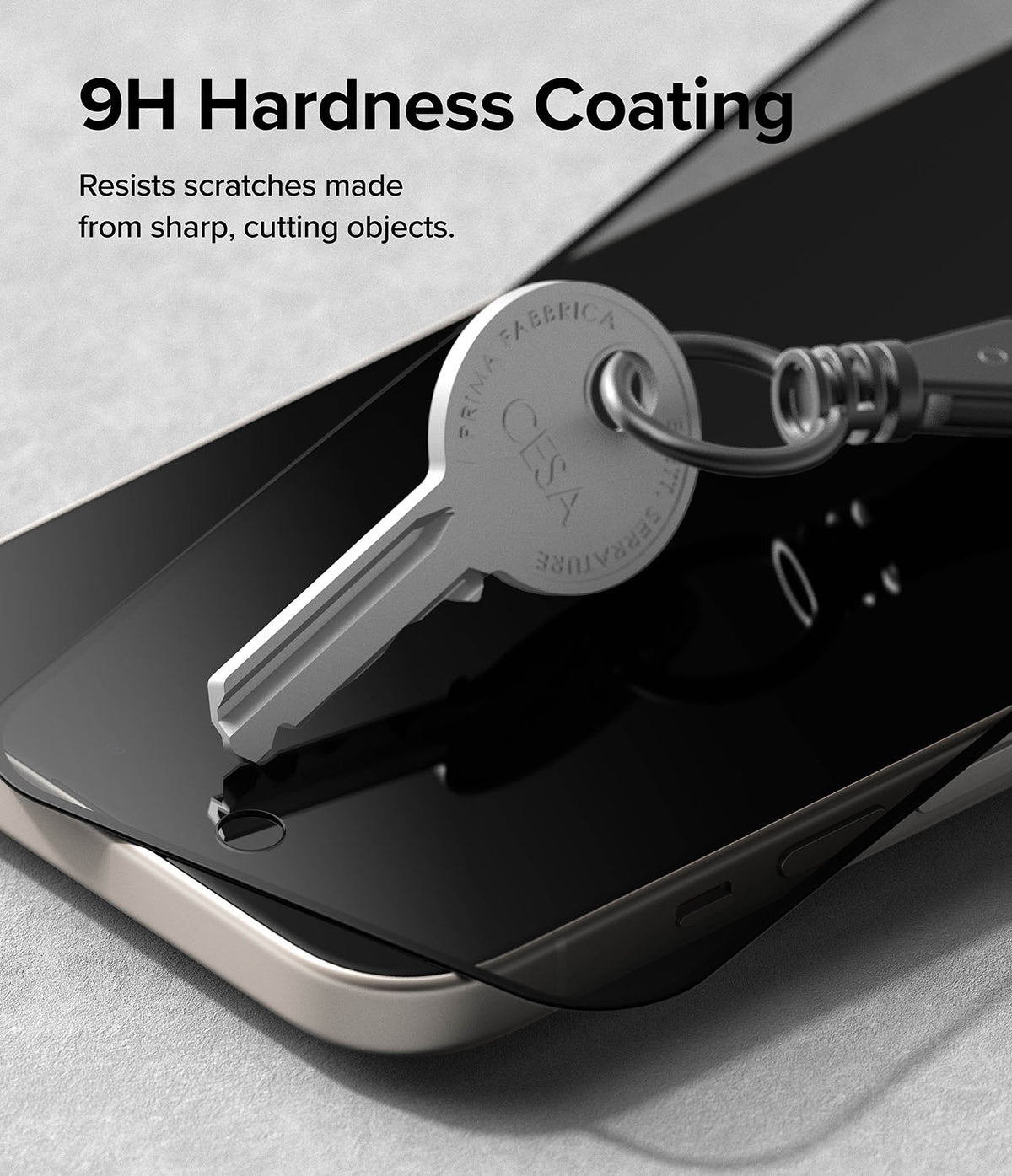 iPhone 15 Screen Protector | Privacy Glass - A metal key resting on a smartphone screen with a 9H hardness privacy protector.