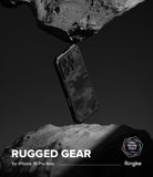 iPhone 16 Pro Max Case | Rugged Gear - Camouflage phone case suspended between two jagged rocks in a black and white studio setting.