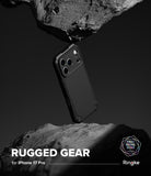 iPhone 17 Pro Case | Rugged Gear - Black phone case suspended between two jagged rocks against a dark background.