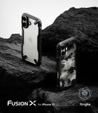 iPhone 17 Case | Fusion-X - Two iPhone 17 cases, one clear and one camo, displayed on dark, rugged volcanic rock.