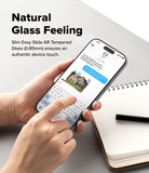 iPhone 18 Pro / Pro Max AR Screen & Camera Protectors all-groups - A person holds a slim smartphone with a transparent glass back, showing a messaging screen, over a light gray surface with a notebook and pen nearby. Text on the image reads 'Natural Glass Feeling' and describes the easy slide AR tempered glass.