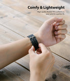 Watch Lug 20mm | Rubber One Band - Person adjusting a flexible black TPU watch strap on their wrist over a wooden table.