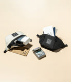 Mini Pouch | Sling Bag - White and black mini pouches filled with cards and small items on a beige background.