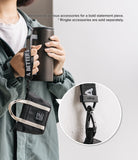 Mini Pouch | Tote Bag - A person holds a black tumbler with a branded strap attached to a small black tote pouch.