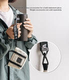 Mini Pouch | Tote Bag - A person holds a tumbler with a branded strap attached to a small beige tote pouch, with a close-up of the clip.