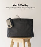 Mini Pouch | 2-Way Bag Miniature - A small beige and black pouch attached to a larger black bag sitting on a wooden stool.