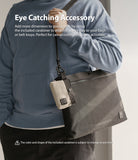 Mini Pouch | 2-Way Bag Miniature - A beige mini pouch clipped to a larger dark grey shoulder bag worn by a person in a blue hoodie.