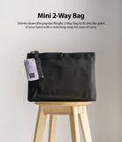 Mini Pouch | 2-Way Bag Miniature - A small lavender pouch attached to a larger black bag, both resting on a wooden stool.