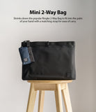 Mini Pouch | 2-Way Bag Miniature - A small navy pouch attached to a larger black bag, both resting on a wooden stool.