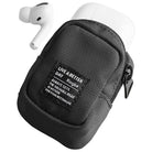 Mini Pouch | Block - Black fabric mini pouch holding white wireless earbuds with a branded label on the front.