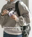 Mini Pouch | Half-Pocket - A person wearing a grey hoodie holds a small lavender pouch attached to their backpack by a carabiner.