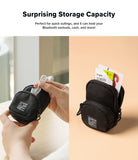 Mini Pouch | Block - Hands placing wired earbuds into a black mini pouch, with another pouch holding cards and a screen wipe.