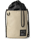 Mini Cross Bag | Bucket Bag - Beige cylindrical bucket bag with black drawstring closure and black rope shoulder straps.